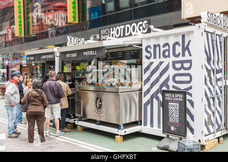 Le persone si mettono in linea per effettuare un acquisto presso lo snack Box, un alimento e bevanda chiosco in Times Square a New York City. Foto Stock