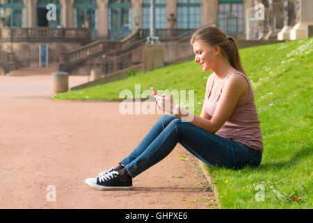 Turista legge le informazioni contenute nello smartphone presso il palazzo Zwinger, Dresda, Germania Foto Stock