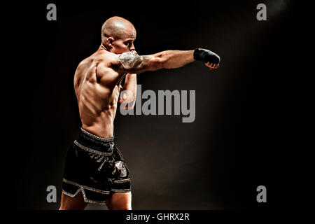 Kickbox muscolare o muay thai fighter punzonatura nelle tenebre Foto Stock