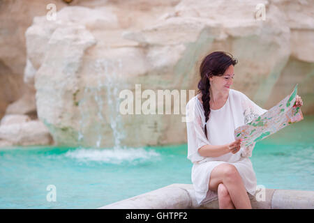 Bella donna guardando citymap turistico vicino a Fontana di Trevi, Roma, Italia. Felice ragazza godere di vacanza italiana vacanza in Europa. Foto Stock