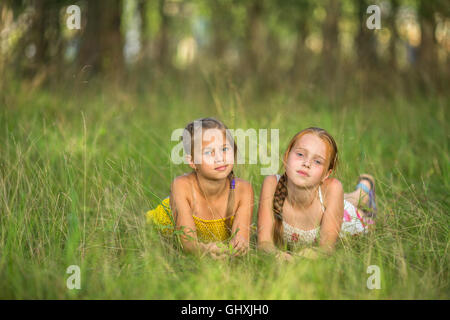 Due piccole sorelle giacente nel prato guardando la telecamera. Foto Stock