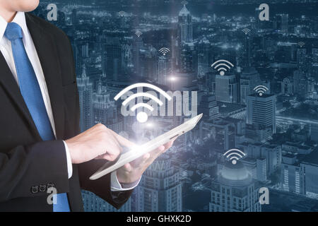 La tecnologia aziendale concetto - Business man premere tavoletta digitale per il collegamento wifi o internet nel centro business district. Foto Stock