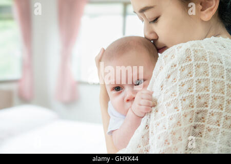 Foto di felice Asian madre kiss neonato bimbo dopo il grido. Primo piano a madre e neonato Bambino. Foto Stock