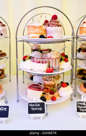 Vista verticale di torte e pasticcini disposti sulla torta si trova di fronte a una sala da tè. Foto Stock