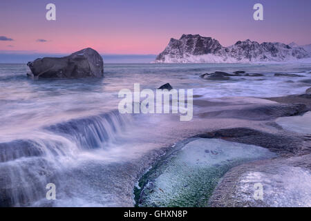 Bella spiaggia Uttakleiv sulle Lofoten in Norvegia settentrionale al tramonto in inverno. Foto Stock