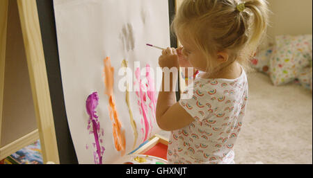 Bambina pittura permanente a un cavalletto Foto Stock