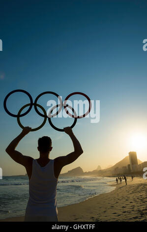 RIO DE JANEIRO - 30 ottobre 2015: atleta detiene anelli olimpici sopra tramonto vista dello skyline della citta' della spiaggia di Copacabana dal Leme. Foto Stock
