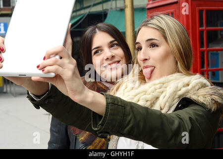 Ritratto di due giovani amiche tenendo selfie con la compressa in un viaggio insieme. Il concetto di turismo. All'esterno. Foto Stock