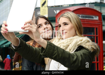 Ritratto di due giovani amiche tenendo selfie con la compressa in un viaggio insieme. Il concetto di turismo. All'esterno. Foto Stock