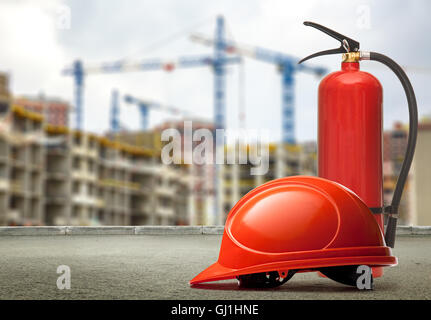 Estintore e casco su edifici e gru background closeup Foto Stock