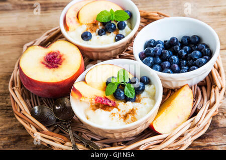 Budino di riso con cannella, i mirtilli, le pesche e le foglie di menta fresca Foto Stock