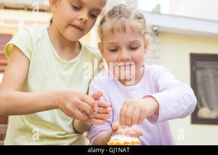 Due ragazze cospargete dolciumi sui tortini di Pasqua Foto Stock