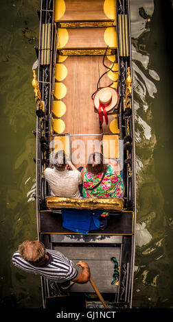 Vista aerea di una coppia seduto su una gondola con il gondoliere vestito con una tradizionale cima a righe. Venezia. Italia. Foto Stock