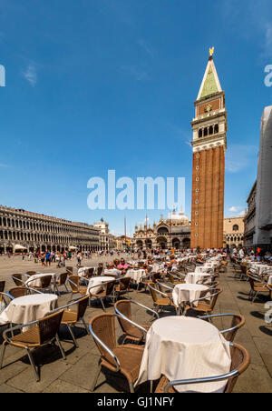 La torre campanaria o campanile di San Marco la Basilica, con tavoli e sedie da Florian's cafe in primo piano.venezia, Italia. Foto Stock