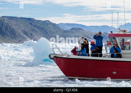 Turisti in gita in barca rossa circondati da ghiaccio marino a Tunulliarfik Fjord fotografando il Qoroq icefjord nell'estate 2016. Narsarsuaq Groenlandia Meridionale Foto Stock