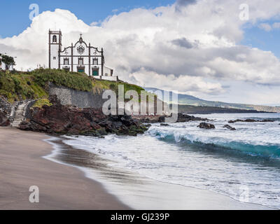 São Roque onde sulla spiaggia e Chiesa. Un ondata di ricci in alla spiaggia tranquilla al di sotto del São Roque chiesa vicino la capitale Azorian. Foto Stock