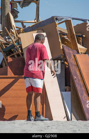 Un uomo aiuta a costruire un falò sulla spiaggia di Los Alcazares per celebrare il Solstizio d'estate, Murcia, Spagna Foto Stock