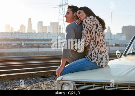 Giovane costeggiata sul cofano auto guarda lontano, Los Angeles, California, Stati Uniti d'America Foto Stock