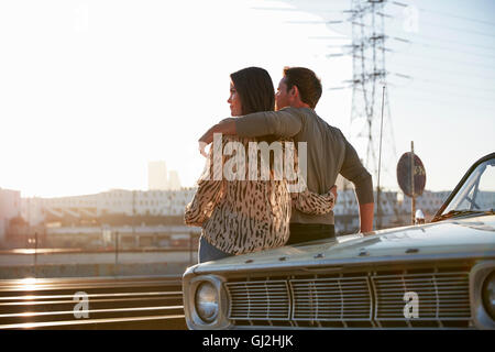 Giovane appoggiata contro il cofano per auto che guarda lontano, Los Angeles, California, Stati Uniti d'America Foto Stock