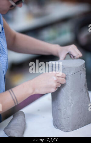 Ritagliato colpo di ceramisti femmina affettamento argilla in officina Foto Stock