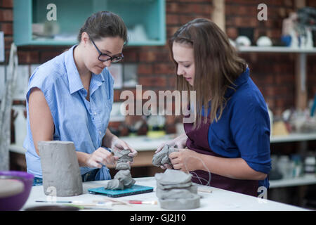 Due femmina potters sagomatura di argilla sul banco di lavoro in officina Foto Stock