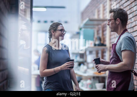 Maschi e femmine di potter chattare in un caffè in officina Foto Stock