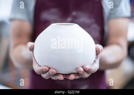 Le mani dei maschi di potter azienda vaso finito in officina Foto Stock