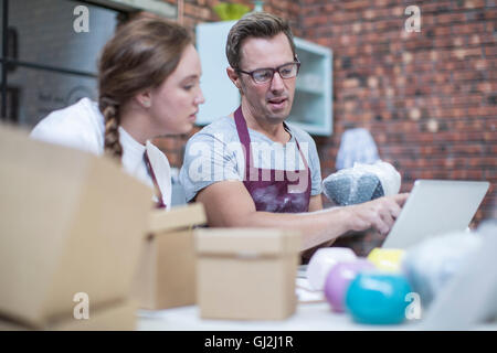 Potter maschio spiegando di imballaggio dei pot online in officina Foto Stock