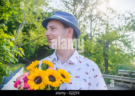 Uomo con fiori che guarda lontano Foto Stock