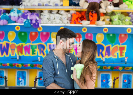 Coppia di fronte a fiera shooting gallery faccia a faccia sorridente, Coney island, Brooklyn, New York, Stati Uniti d'America Foto Stock