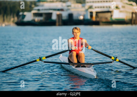 Giovane uomo di canottaggio scull unico sul Puget Sound, Winslow, Bainbridge Island, nello Stato di Washington, USA Foto Stock