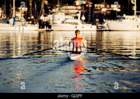 Giovane uomo di canottaggio scull unico sul Puget Sound, Winslow, Bainbridge Island, nello Stato di Washington, USA Foto Stock