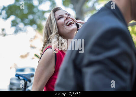 Imprenditrice a parlare e ridere sul cellulare in città Foto Stock