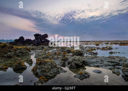 Sunrise colorati e pietre in bassa marea di acqua oceanica Foto Stock