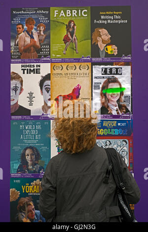 Un rosso donna dai capelli leggendo i manifesti per la mostra presso il underbelly, parte dell'Edinburgh Fringe Festival. Foto Stock