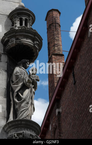 La madre e il bambino (Maria e il bambino Cristo) scultura in pietra che ornano la parete esterna di un edificio a Bruges. Foto Stock