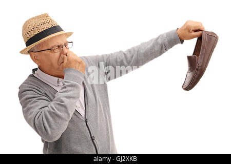 Disgustato vecchio uomo tenendo un puzzolente calzatura isolati su sfondo bianco Foto Stock