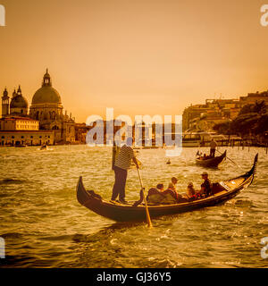 Gondola sul Canal Grande al tramonto, con Santa Maria della Salute in distanza. Venezia. L'Italia. Foto Stock