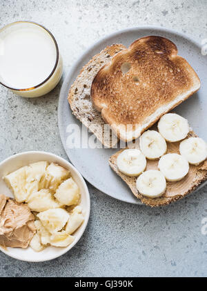 Vista aerea del pane tostato con burro di arachidi, banana e latte Foto Stock