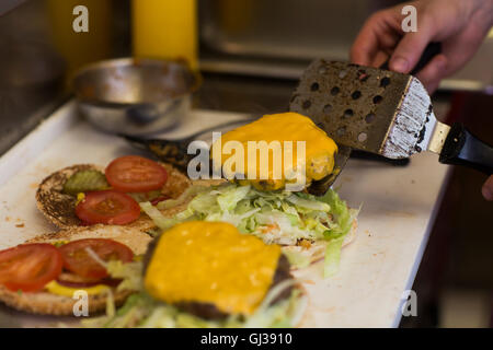 Mano d'uomo preparare cheeseburger in un fast food van cucina Foto Stock