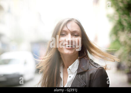 Carefree donna con lunghi capelli oltremare sulla strada di città Foto Stock