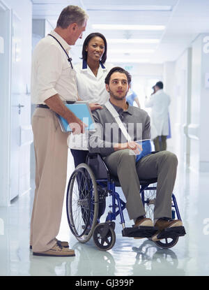 Consulenza medico con uomo in sedia a rotelle con imbracatura del braccio Foto Stock