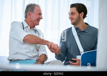 Medico stringono le mani con l uomo nel braccio imbracatura Foto Stock