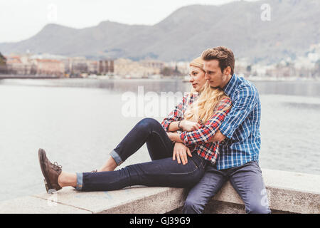 Romantico coppia giovane seduto sulla parete del porto, Lago di Como, Italia Foto Stock