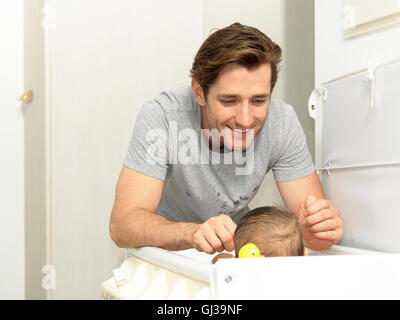 Padre sorridente modifica baby boys pannolino Foto Stock