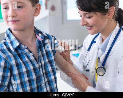 Medico ragazzo lenitiva dopo la vaccinazione in clinica Foto Stock