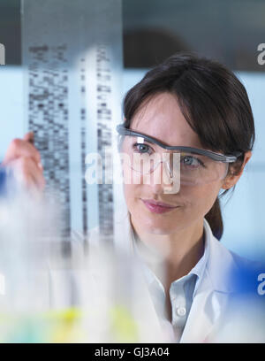 Ricercatore in possesso di un gel di DNA durante un esperimento genetico in un laboratorio Foto Stock