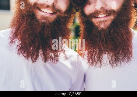 Ritagliato Ritratto di giovane maschio hipster gemelli con la barba rossa indossare magliette di colore bianco Foto Stock