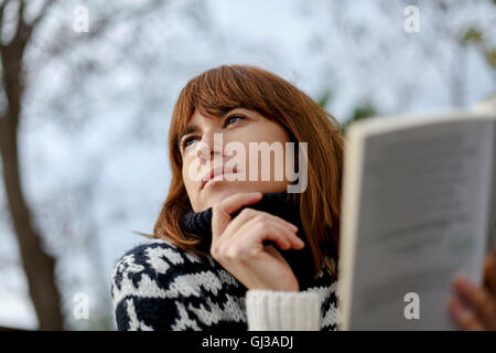 Donna azienda prenota guardando lontano Foto Stock