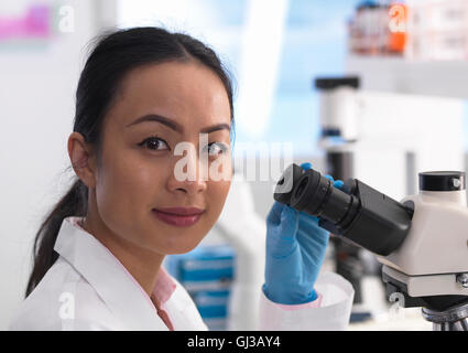 Scienziato visualizzazione di un vetrino di vetro contenente un campione per analisi di laboratorio Foto Stock